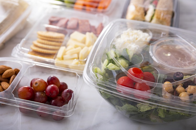 clear compartment containers holding salad, fruits, and cheese