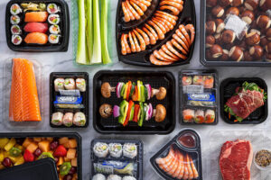 Black tray containers with kabobs, shrimp, and steaks